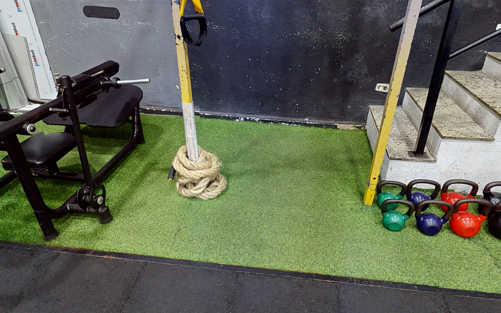 Espaço funcional com grama sintética, corda naval e kettlebells