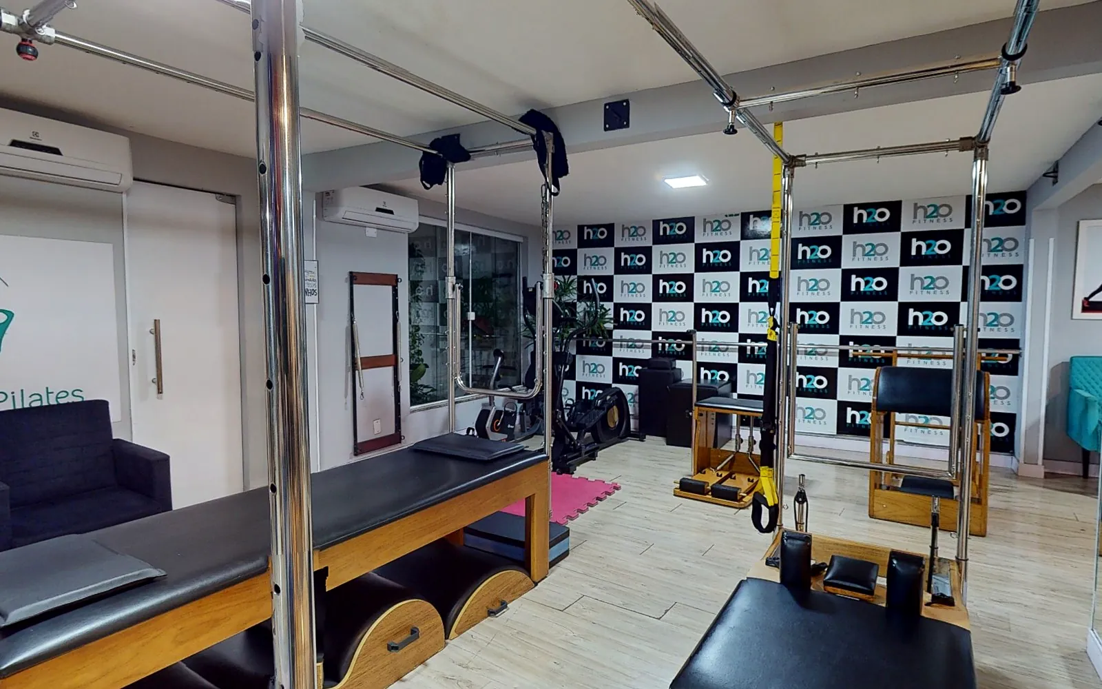 Studio de pilates da H2O com cadillac e painel da marca ao fundo