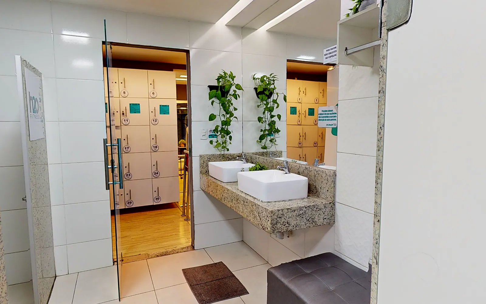 Vestiário da H2O Fitness com bancada de granito e cubas